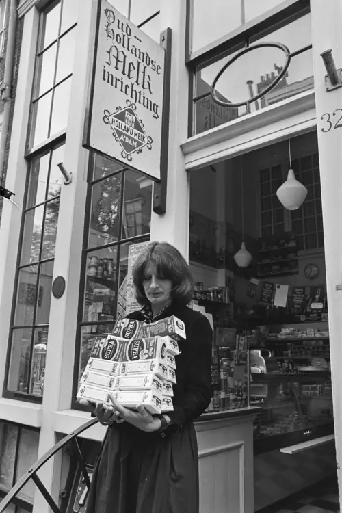 Een vrouw loopt een winkel in Amsterdam uit met een stapel pakken koffie in haar armen.